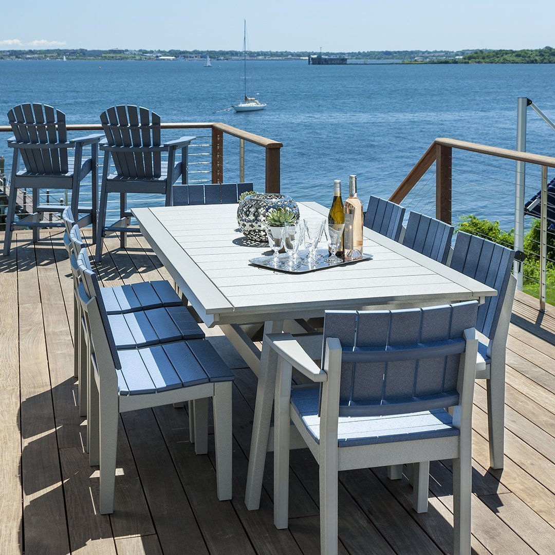 Light gray table and blue chairs set against a waterfront backdrop, showcasing a clean, coastal aesthetic.