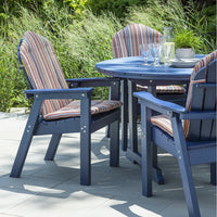 Blue outdoor dining set with striped cushions in vibrant colors, set against lush greenery. Perfect for patio decor.