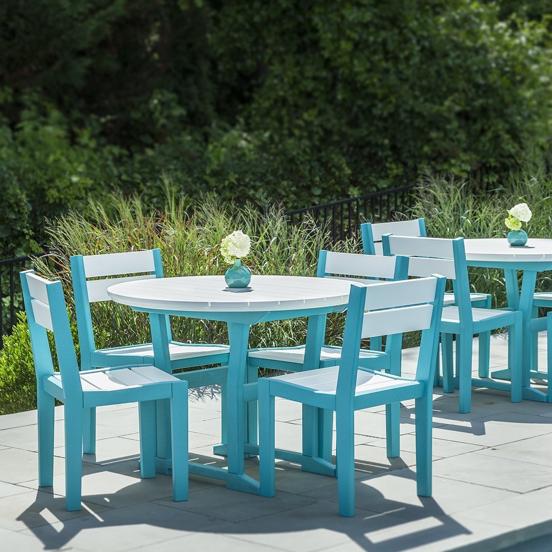 Vibrant turquoise outdoor dining set with matching chairs and table on a stone patio, surrounded by greenery.