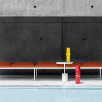 Orange cushions on a modern white bench, complemented by bright yellow and red accents against a gray background.