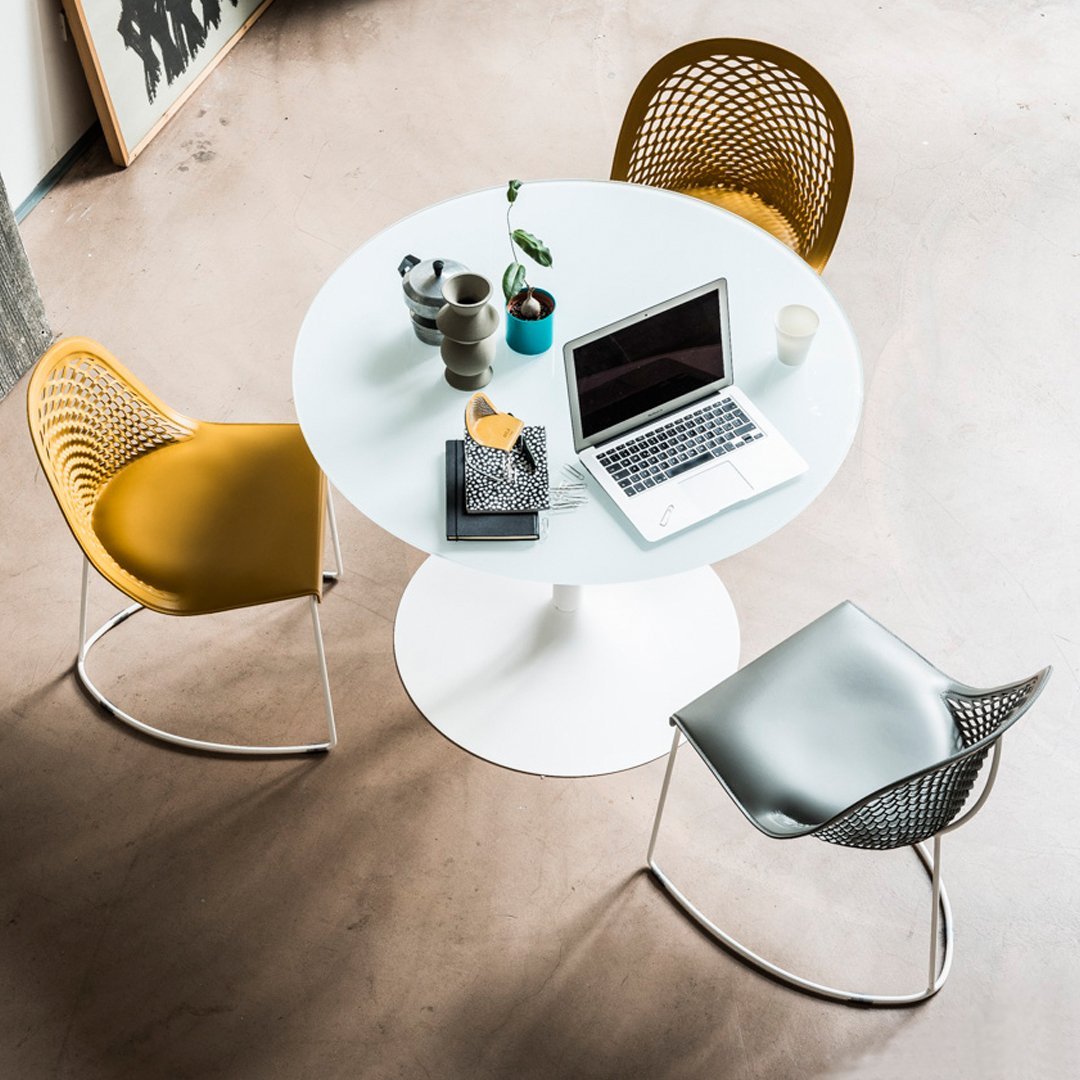 White round table with sleek silver and yellow chairs, featuring geometric patterns and a clean, modern aesthetic.