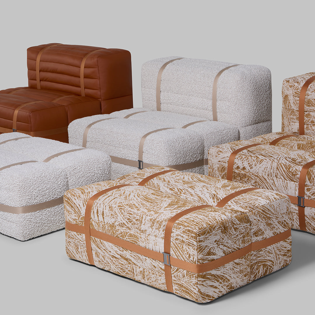 Colorful furniture with brown leather, textured white, and patterned orange and cream upholstery, featuring stylish straps.