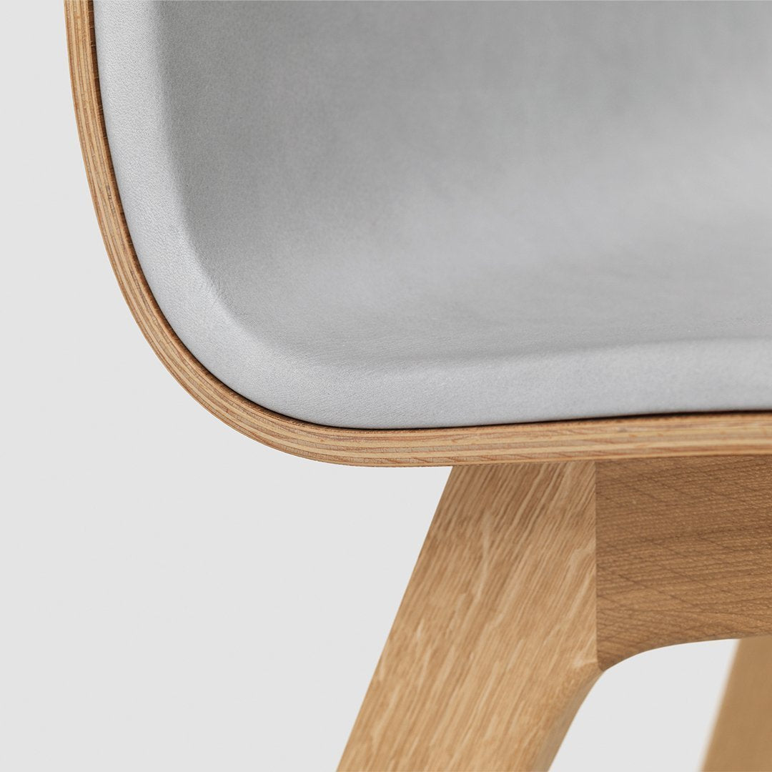 Light gray upholstery with smooth curves, contrasted by a natural wood finish for a modern look.