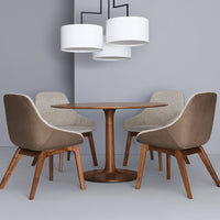 Modern round wooden dining table with beige upholstered chairs and white pendant lights against a gray background.