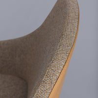 Close-up of a light brown chair with a textured pattern and contrasting yellow stitching along the edge.