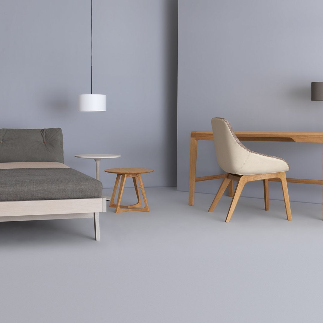 Modern gray room featuring a gray sofa, beige armchair, wooden desk, and light fixtures, complemented by a soft color palette.