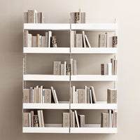 White shelving unit with neutral-toned books and textured patterns, arranged in a modern minimalist design.