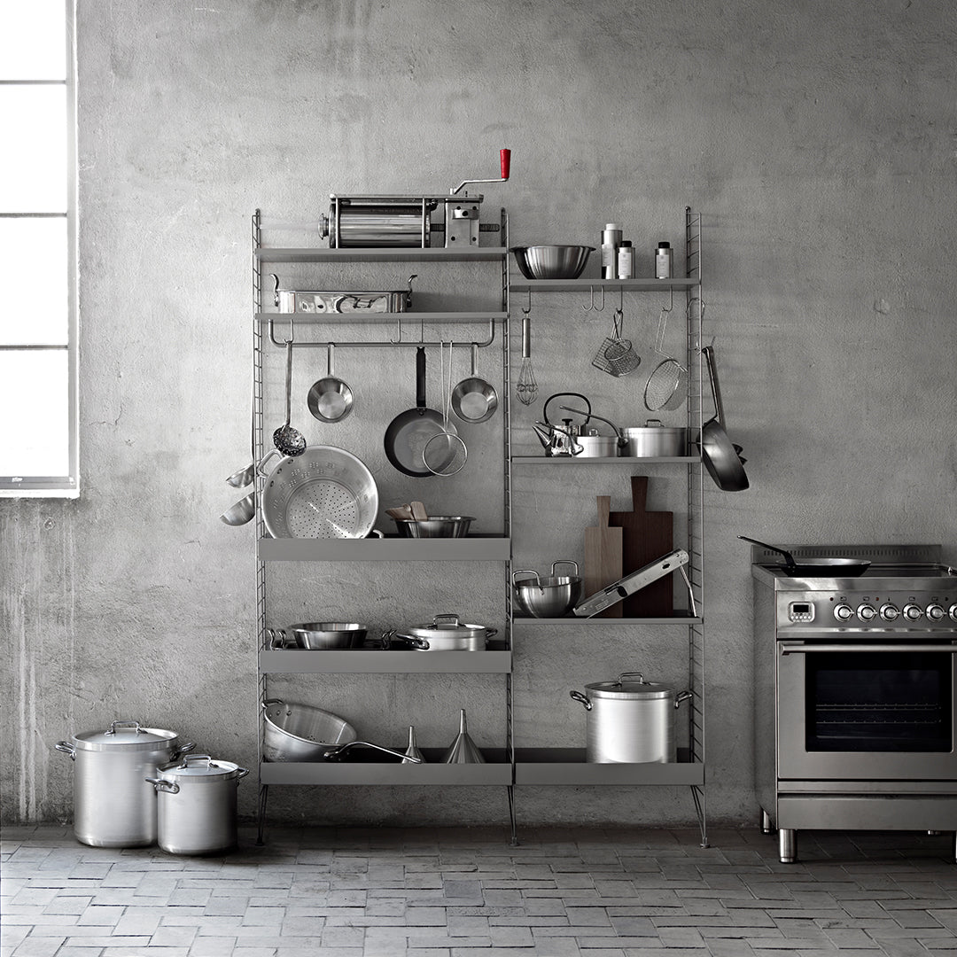 Stylish metal shelving unit with a minimalist silver finish, showcasing various sleek kitchenware against a gray backdrop.