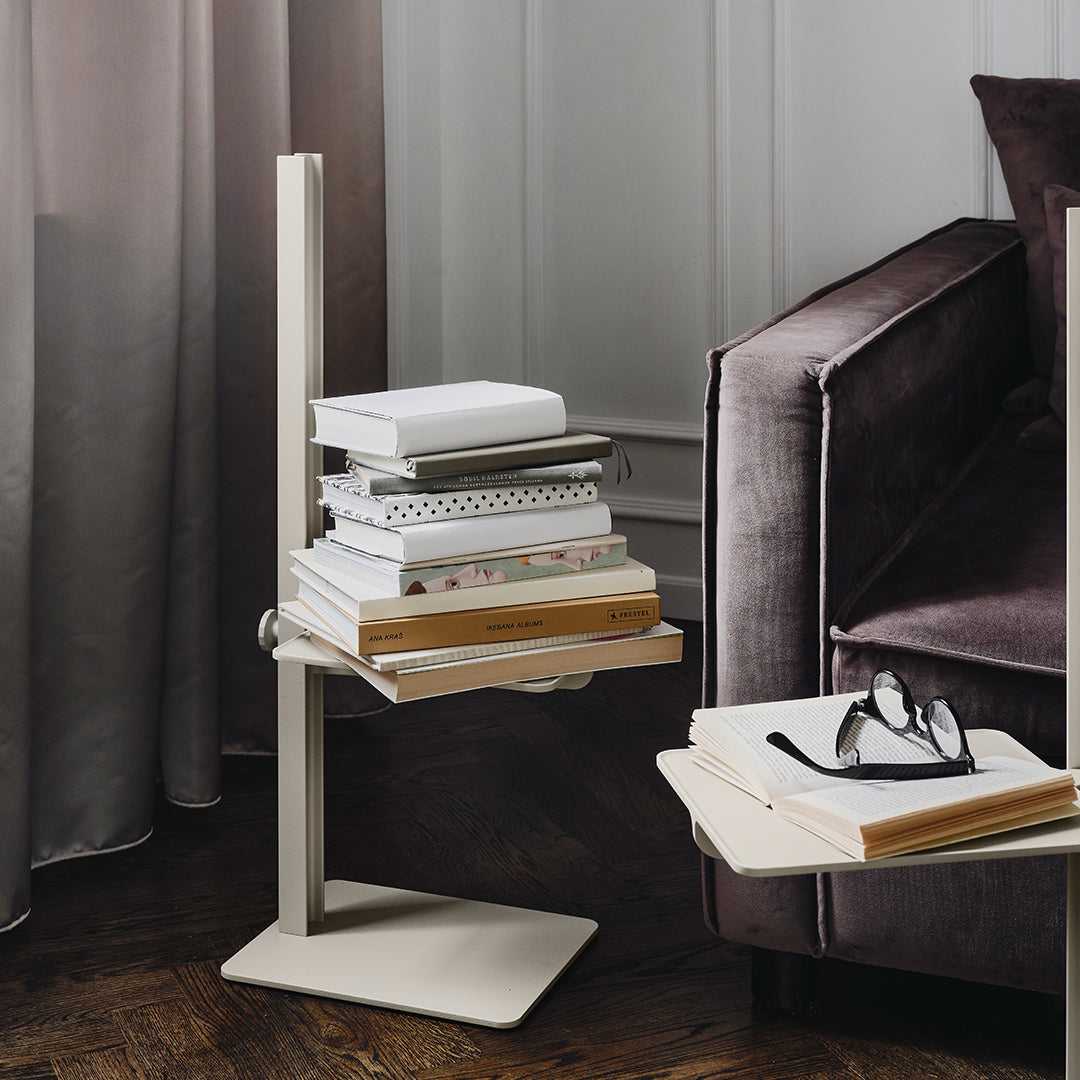 Minimalist beige side table with stacked books, set against a background of rich gray and soft textures.