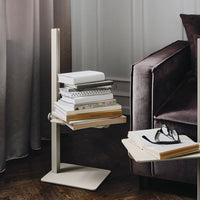 Minimalist beige side table with stacked books, set against a background of rich gray and soft textures.