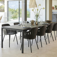 Black dining table with sleek lines paired with coordinating black ribbed chairs. Neutral backdrop enhances modern look.