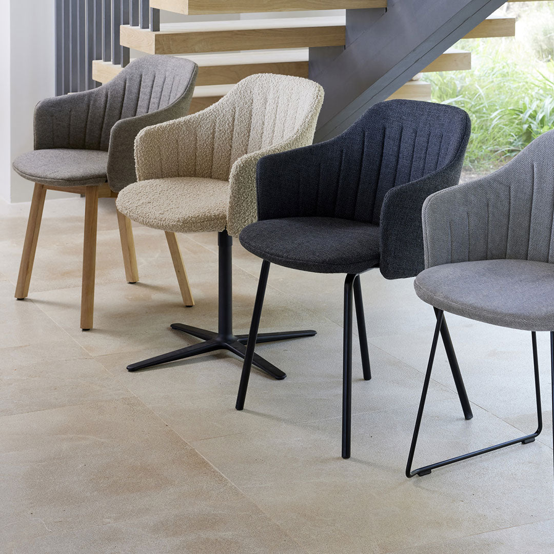 "Set of four modern chairs in beige, gray, and black with textured upholstery and stylish leg designs."