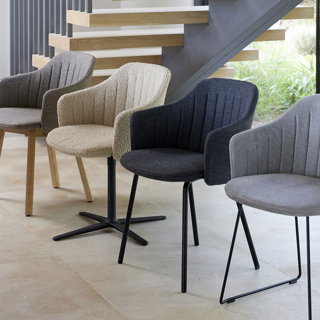 Set of four upholstered chairs in gray, beige, and black, featuring ribbed patterns and varying leg styles.