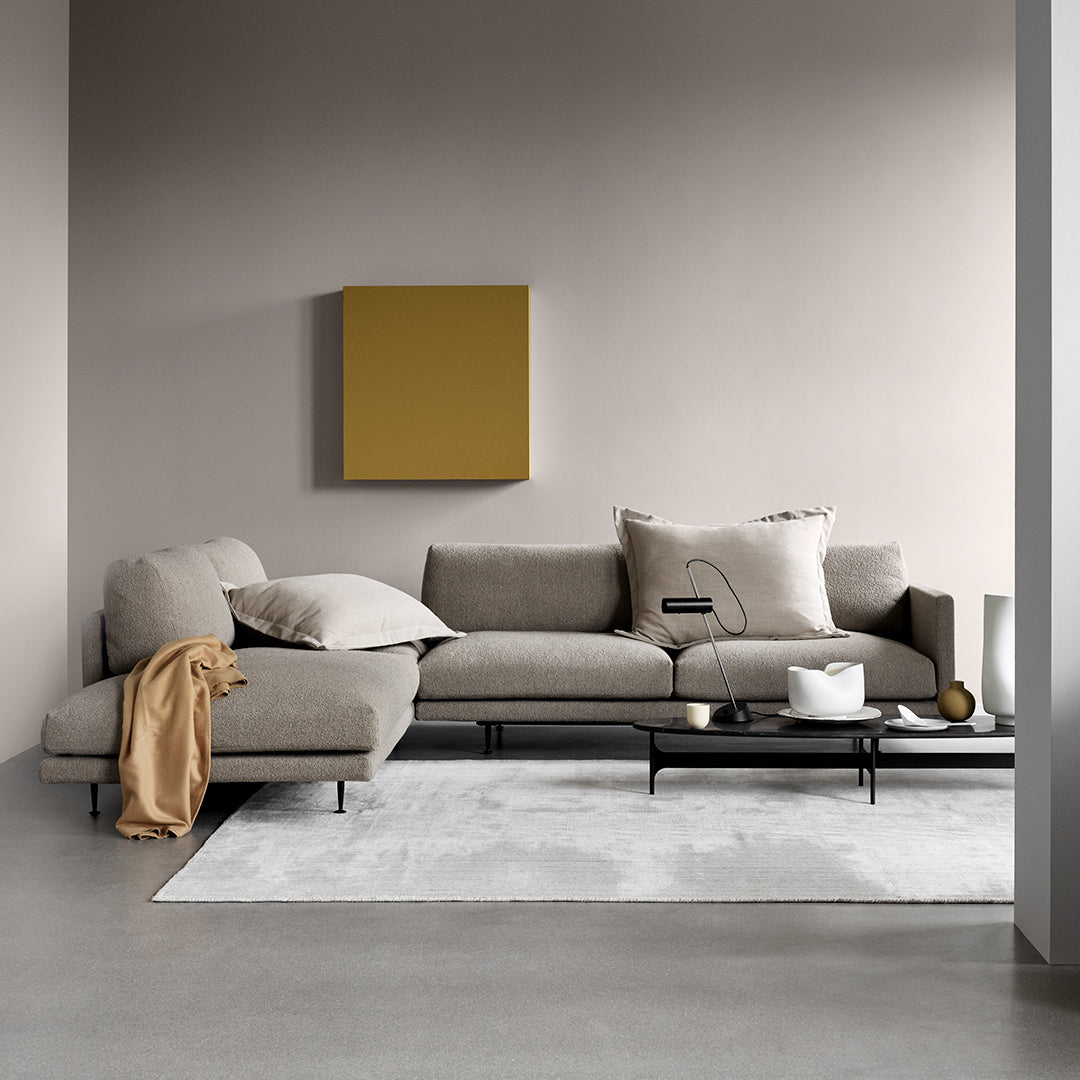 "Light gray sectional sofa with neutral cushions, accentuated by a mustard wall art and soft white area rug."
