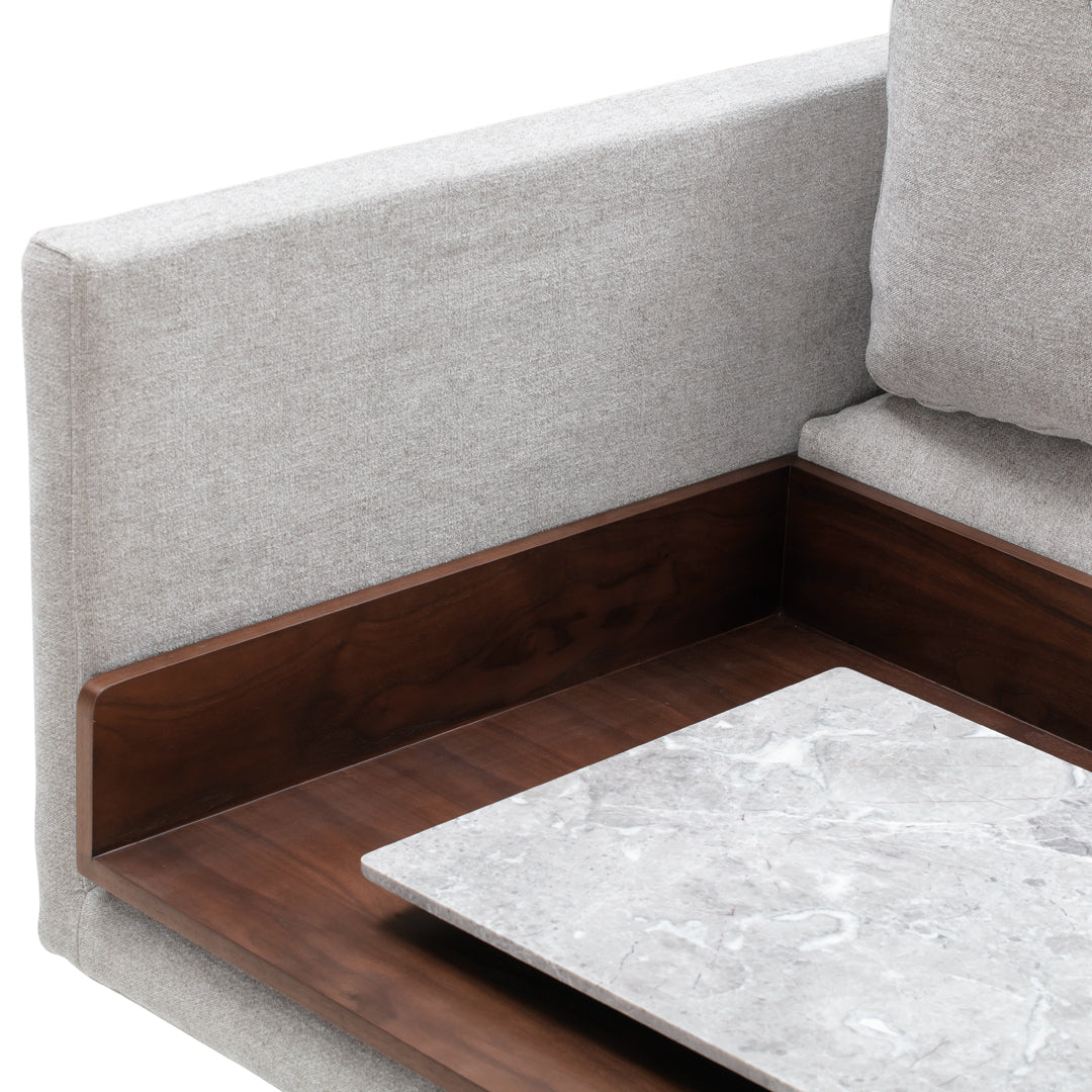 Light gray upholstered couch corner with wooden accents and a marble tabletop. Modern and sleek design.