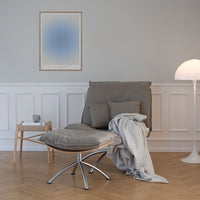 Gray upholstered chair with cushions and soft throw, minimalist decor with light wood and soft gray accents.