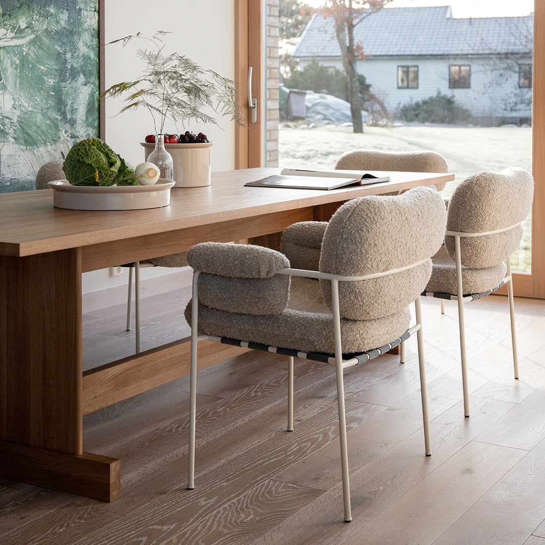 Soft beige chairs with textured upholstery, paired with a natural wood table in a bright, modern dining space.