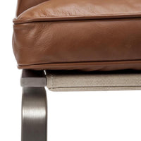Brown leather cushion on a sleek metal frame, featuring a textured light beige fabric underneath.