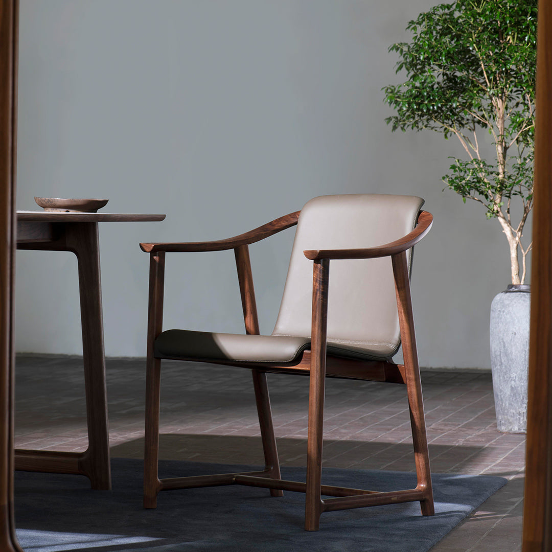 Beige leather armchair with a sleek wooden frame, set against a neutral backdrop and a soft blue rug. 