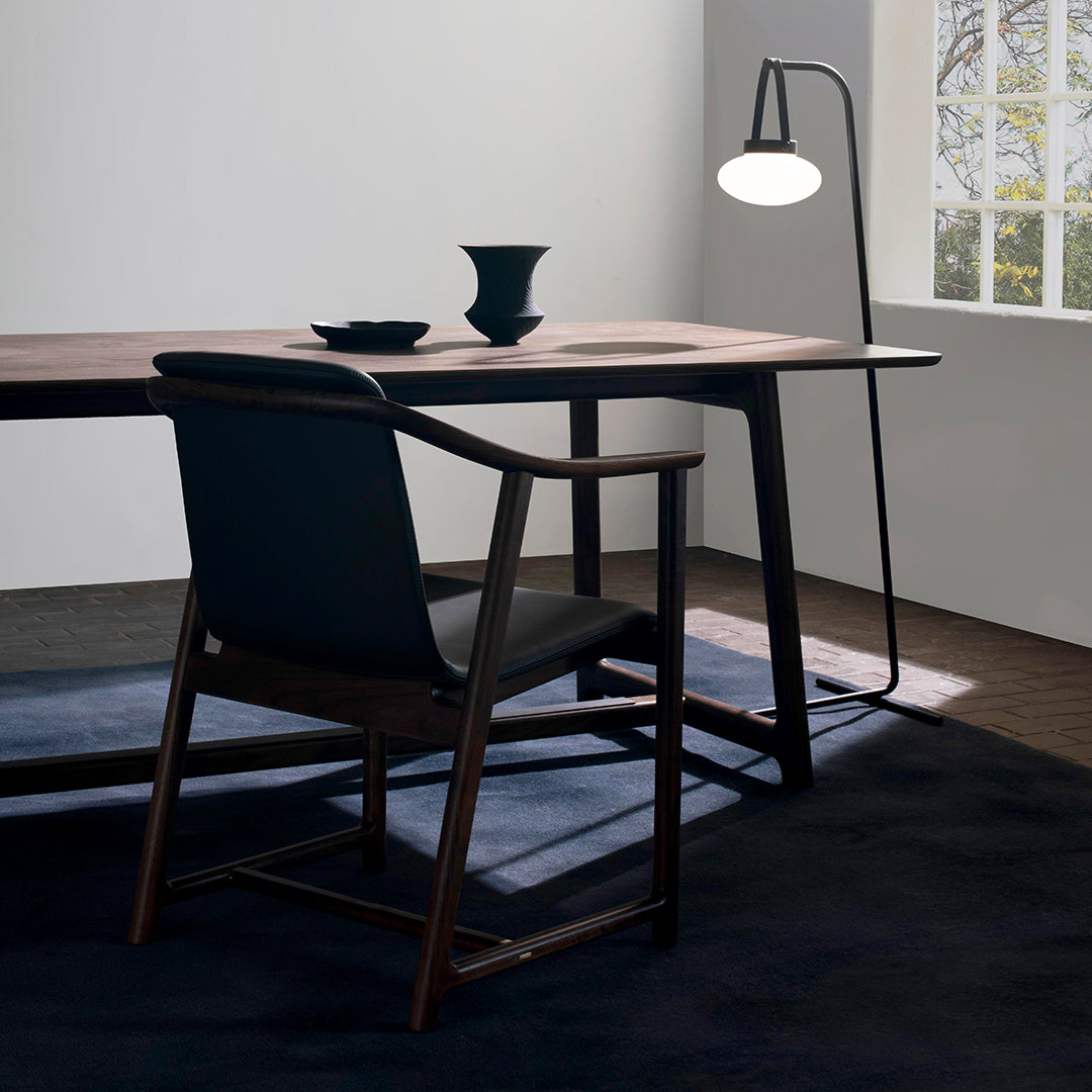 Stylish black chair and table with dark wood and navy accents, complemented by a minimalist lamp and geometric decor.