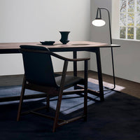 Stylish black chair and table with dark wood and navy accents, complemented by a minimalist lamp and geometric decor.