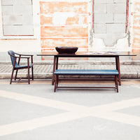 Stylish wooden dining table with dark finish and blue cushions, featuring clean lines and modern design.