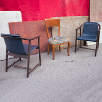 "Three vintage chairs: two dark blue with wood frames and one patterned seat with orange, yellow, and blue stripes."