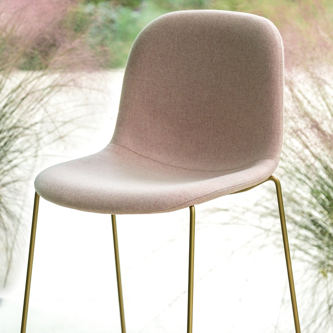 Blush pink upholstered chair with a smooth surface and sleek gold metal legs, perfect for modern decor.
