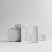 White ceramic tableware set with modern shapes and smooth textures, featuring various minimalist designs.