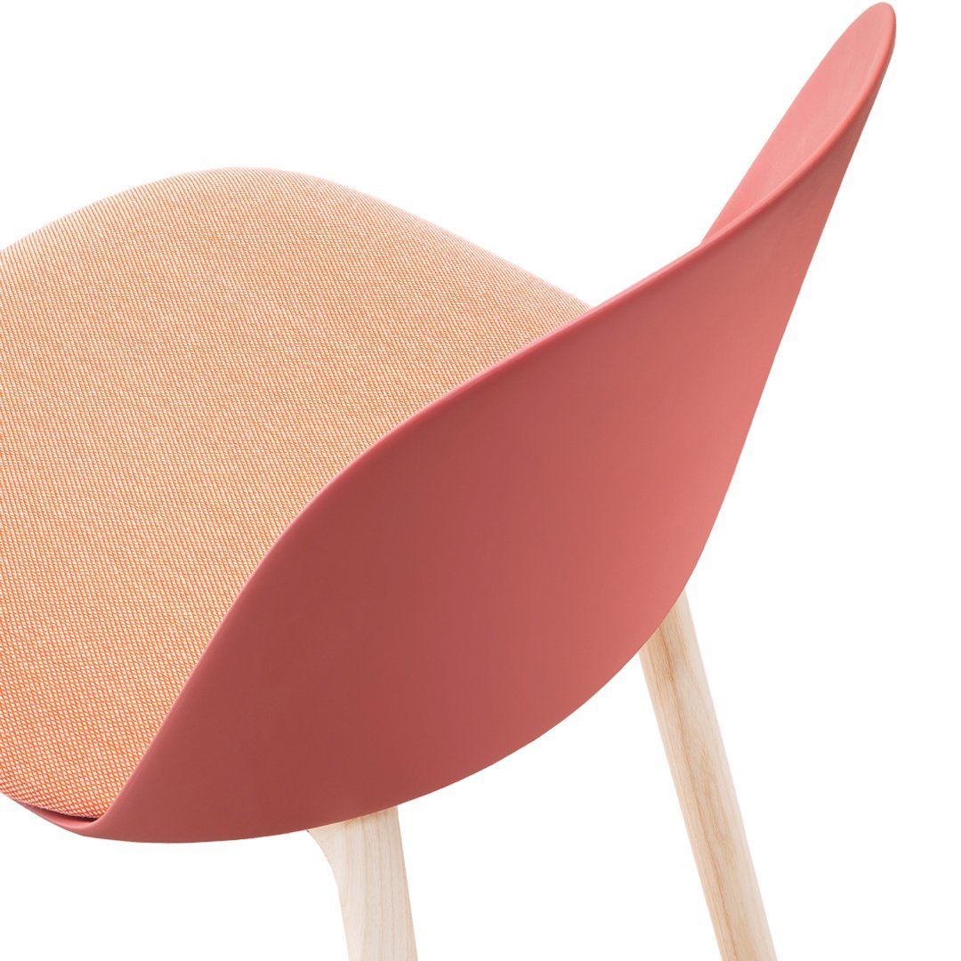 Coral pink seat with a textured peach upholstery and light wooden legs, offering a modern, stylish look.