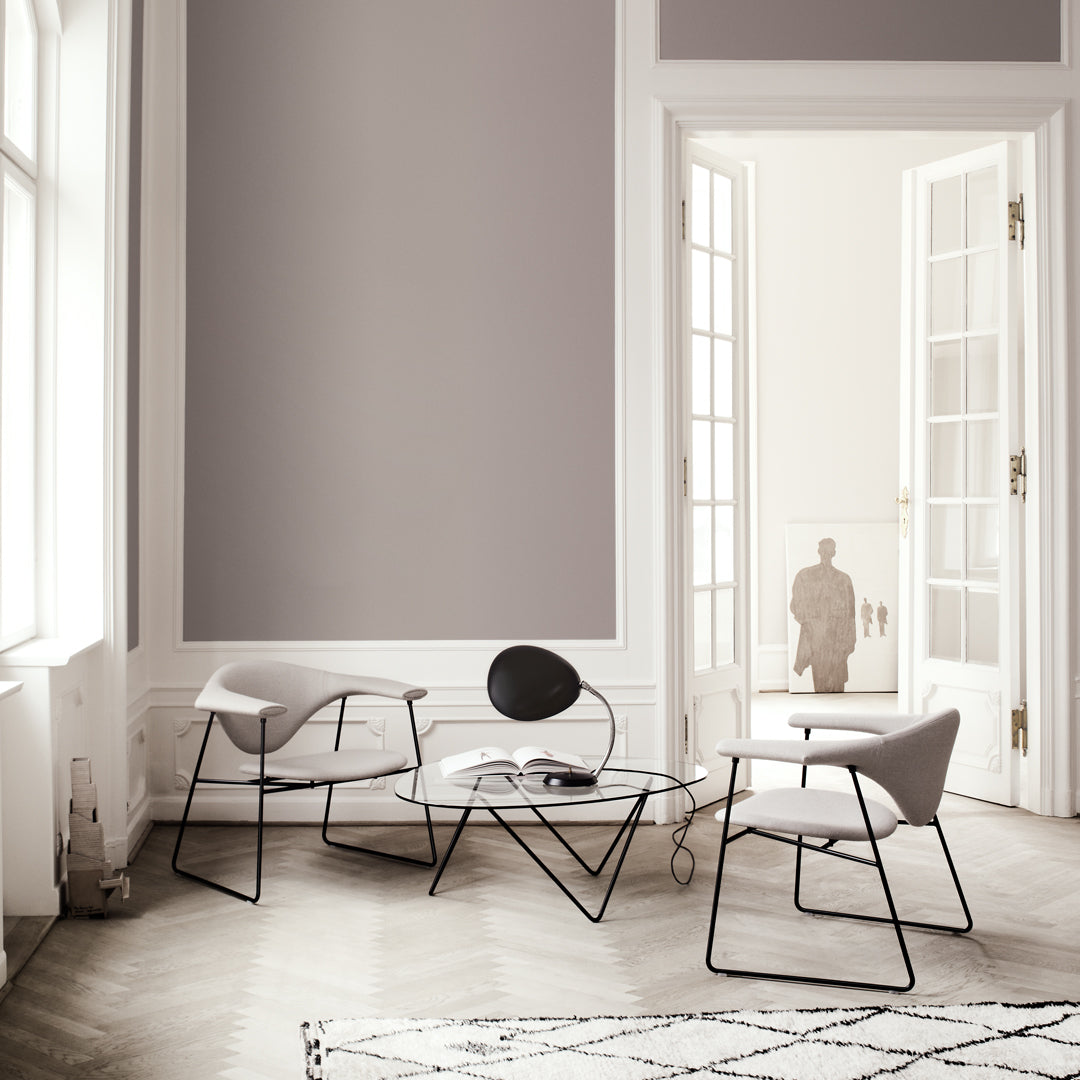 Light gray walls, minimalist black and gray furniture, and a geometric patterned rug create a modern, stylish ambiance.