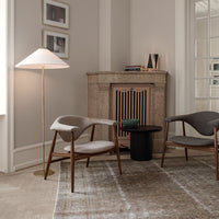Cozy living room with neutral beige and gray chairs, a black side table, and a light wood floor featuring subtle patterns.
