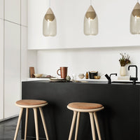 Modern kitchen with black and white colors, wooden accents, and soft beige pendant lights. Stylish and minimalist design.