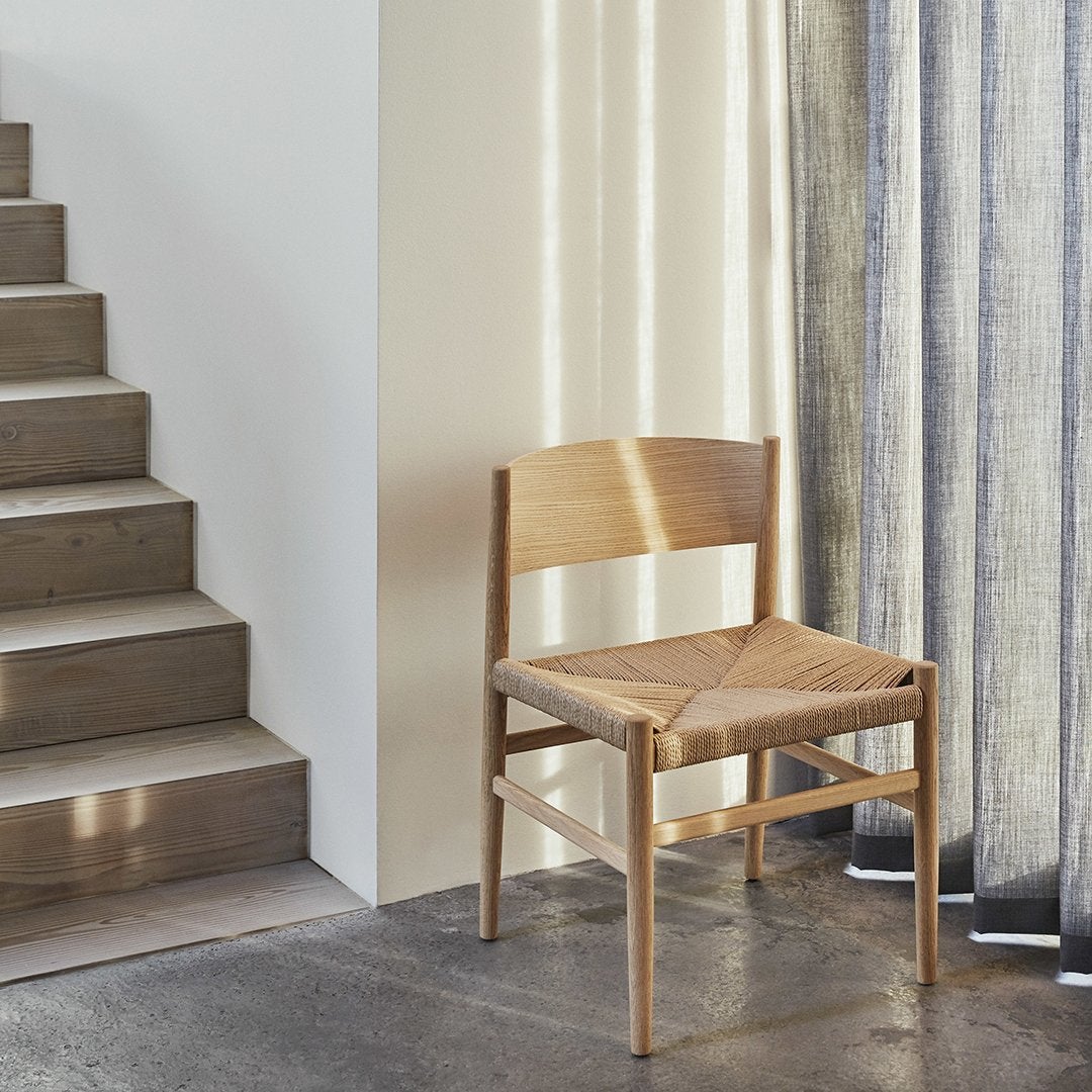Natural wood chair with a woven seat, featuring neutral tones and subtle textures against a light backdrop.