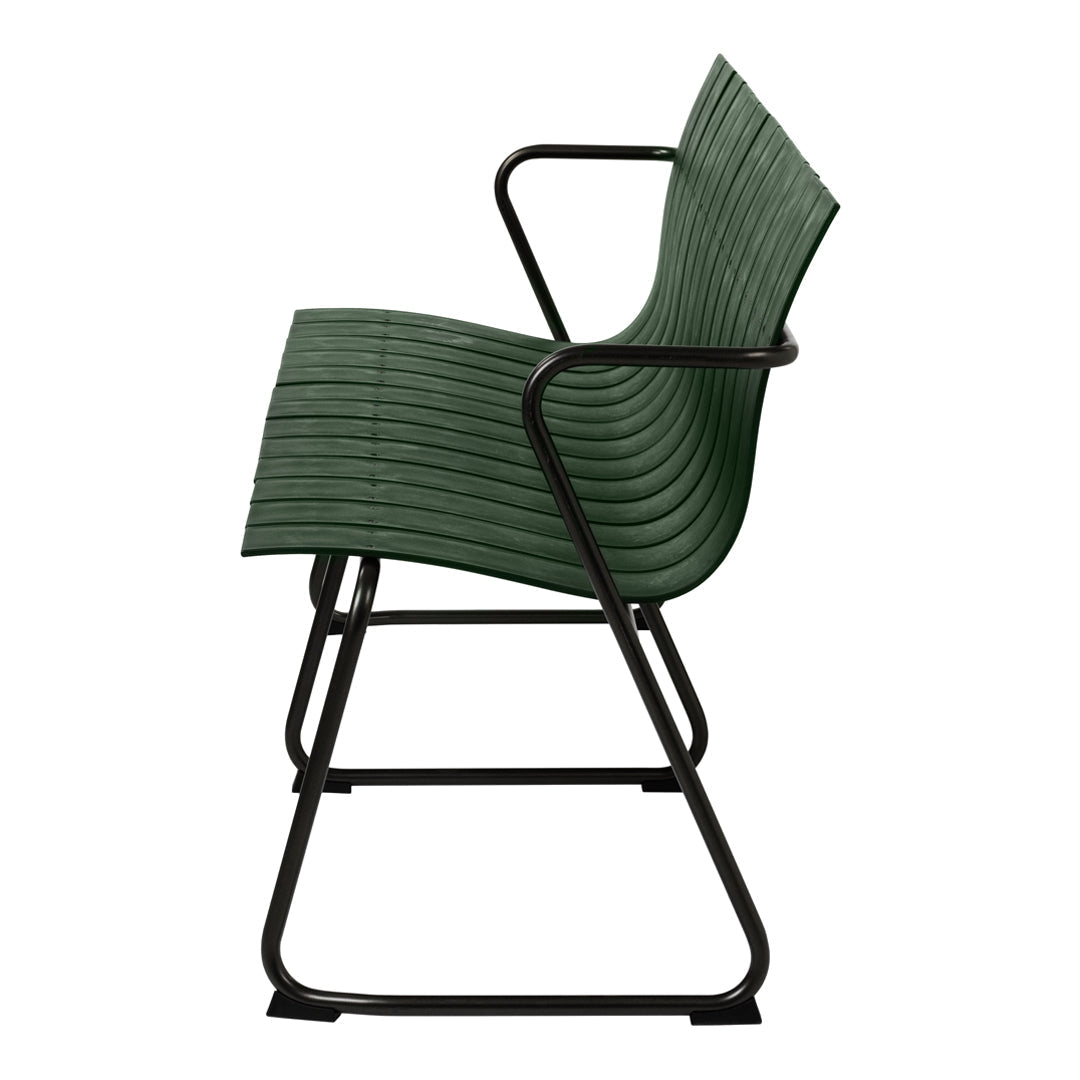 Green ribbed chair with a sleek black metal frame, showcasing a modern design and textured surface.