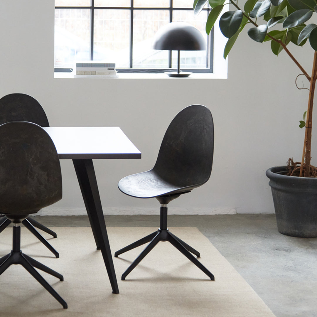 Black modern chair with a smooth curved seat, paired with a minimalistic white table and neutral rug in a stylish interior.