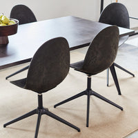 Black curved chairs with matte finish and sleek black bases, set around a minimalist wood dining table.