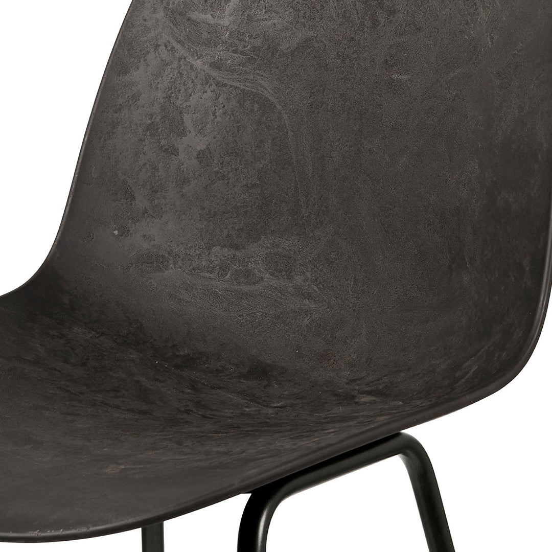 Textured black chair seat with a subtle matte finish, showcasing a modern, minimalist design.