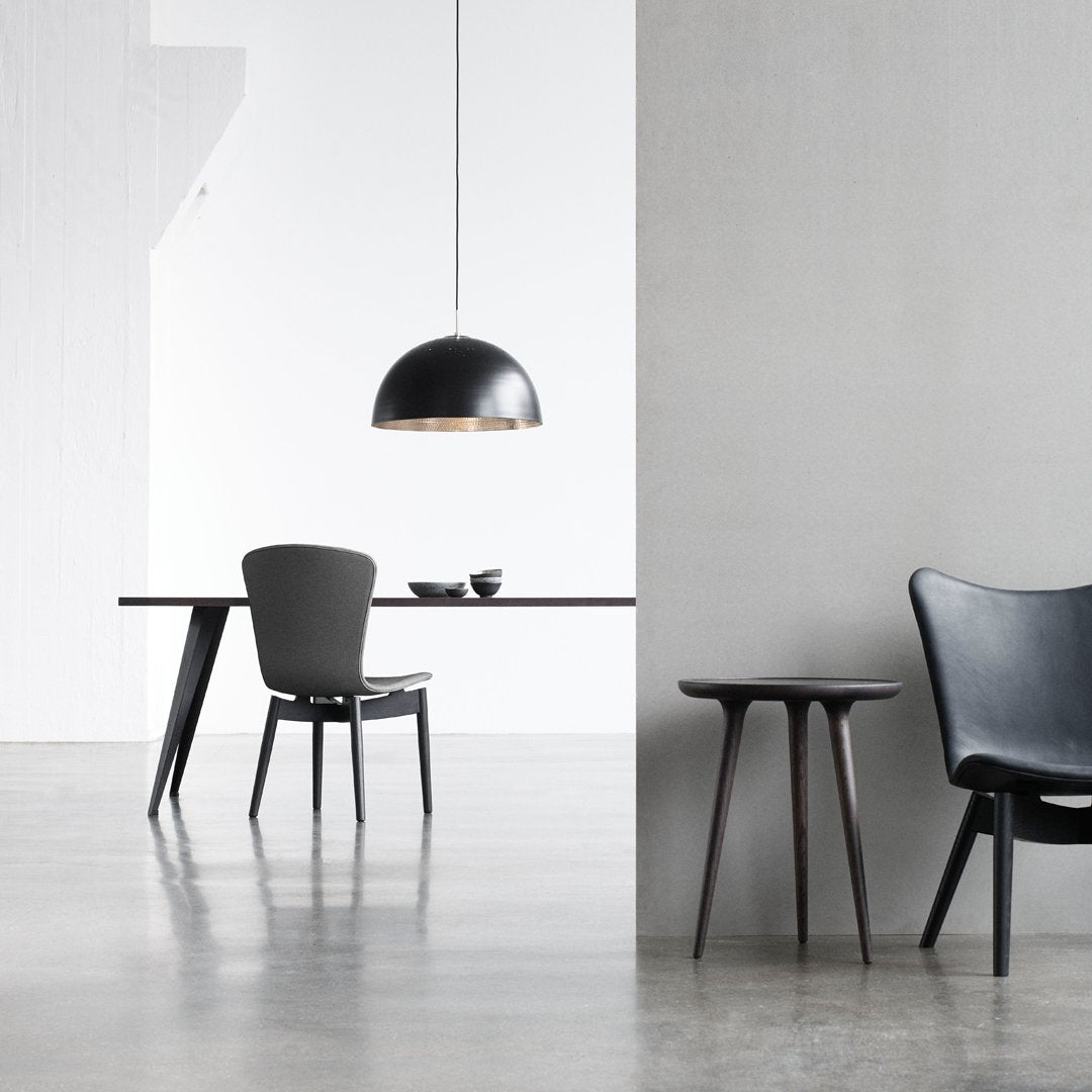 Stylish black dining chair and table set with sleek, modern lines against a light gray and white backdrop.