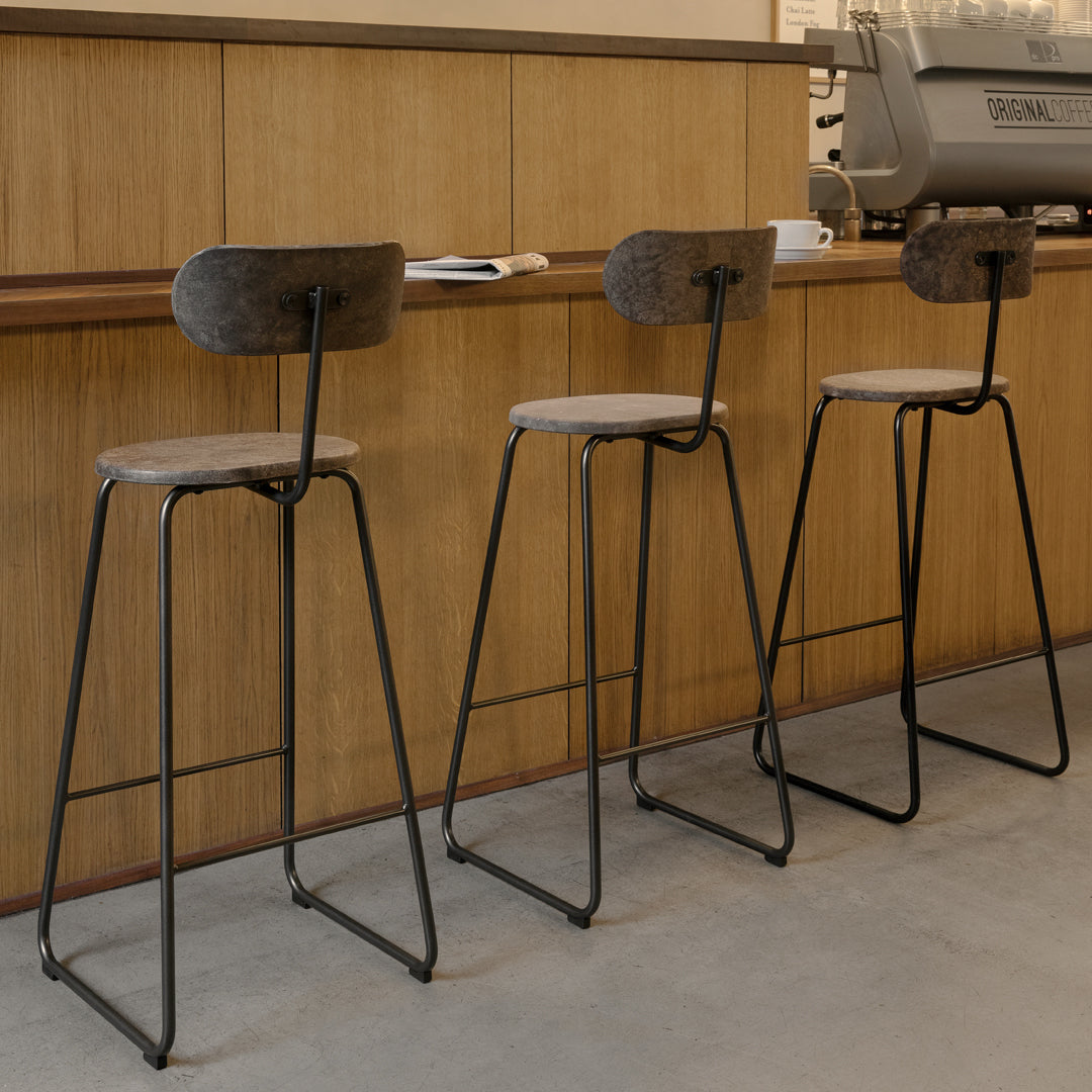 Three modern bar stools with black metal frames and beige upholstered seats, featuring a textured pattern on the backs.
