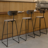 Three modern bar stools with black metal frames and beige upholstered seats, featuring a textured pattern on the backs.