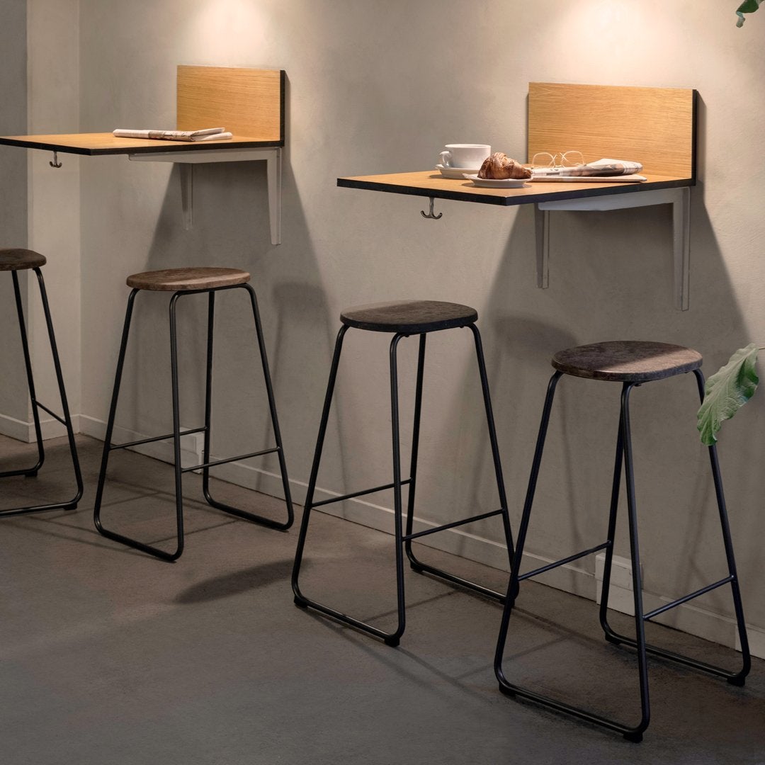 Stylish bar stools with sleek black frames and wooden seats paired with elegant wooden wall-mounted tables.