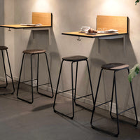 Modern bar stools with black metal frames and wooden seats, paired with natural wood wall-mounted tabletops.