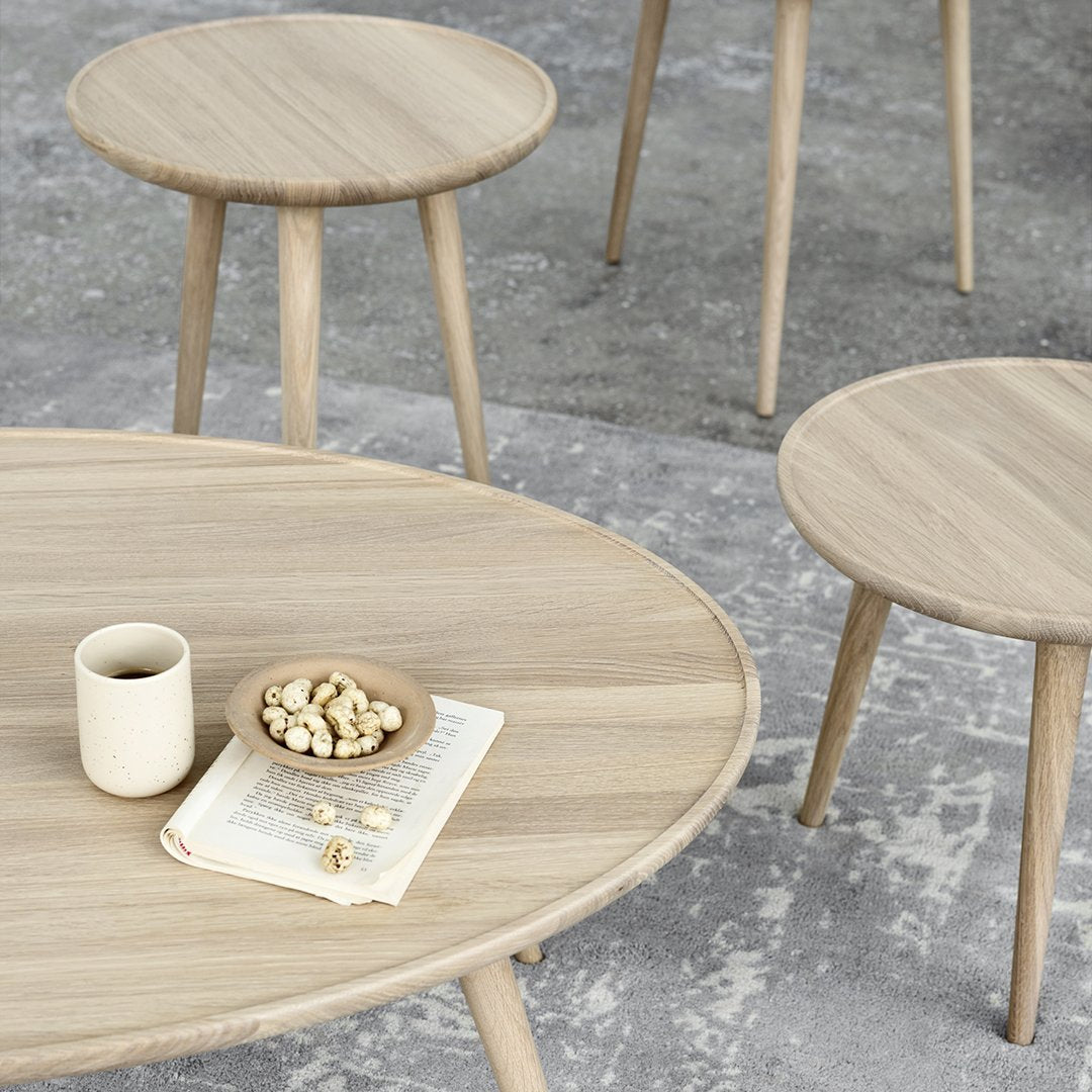 Light oak wood coffee and side tables with smooth, clean lines on a textured gray surface.