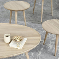 Light oak wood coffee and side tables with smooth, clean lines on a textured gray surface.