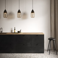Modern black kitchen cabinet with wood countertop, featuring dark glass pendant lights and a textured floor pattern.