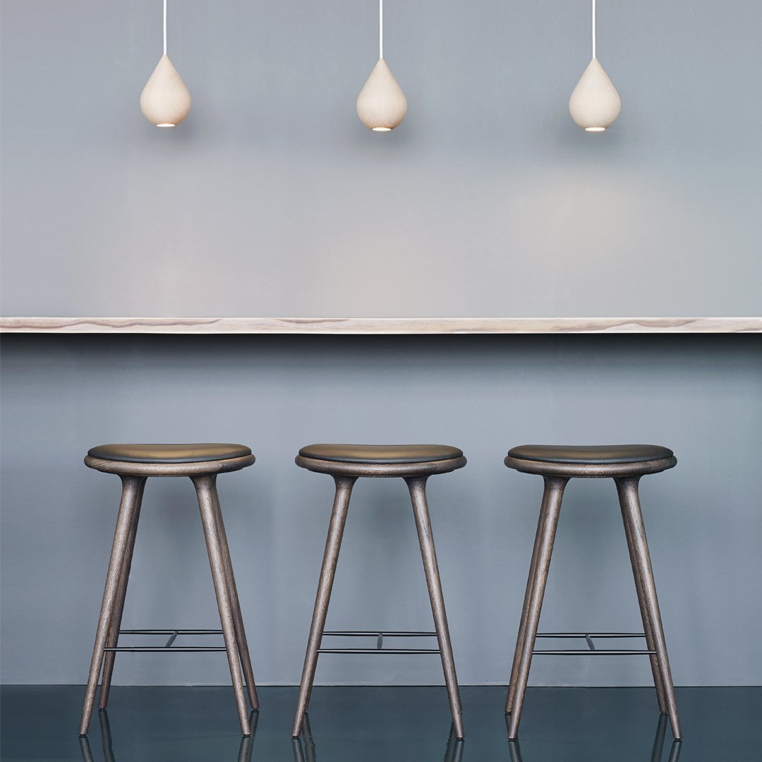 Set of three sleek gray stools against a soft blue background, complemented by white pendant lights.