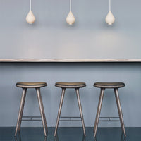 Set of three sleek gray stools against a soft blue background, complemented by white pendant lights.