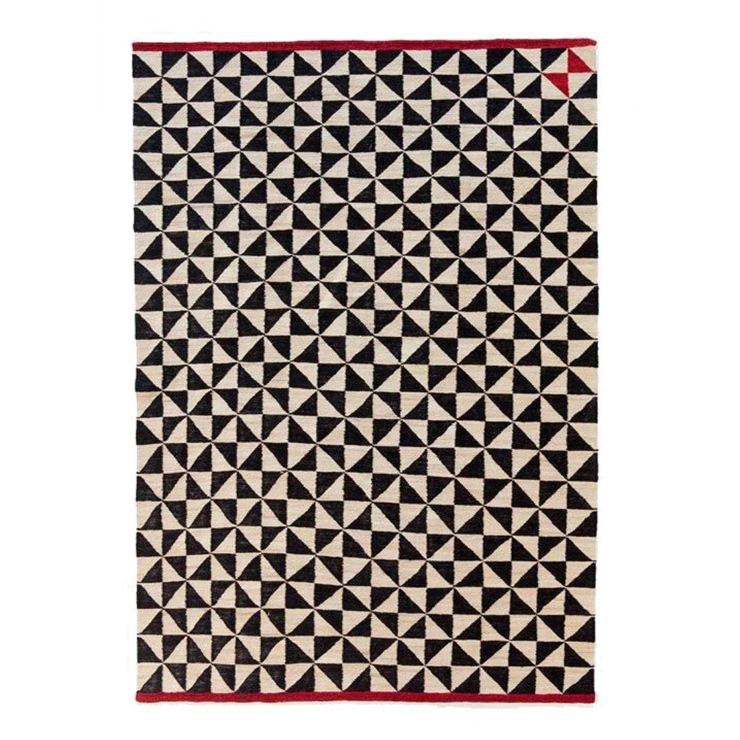 Black and cream geometric pattern with red accents on a textured rug. Perfect for modern decor.