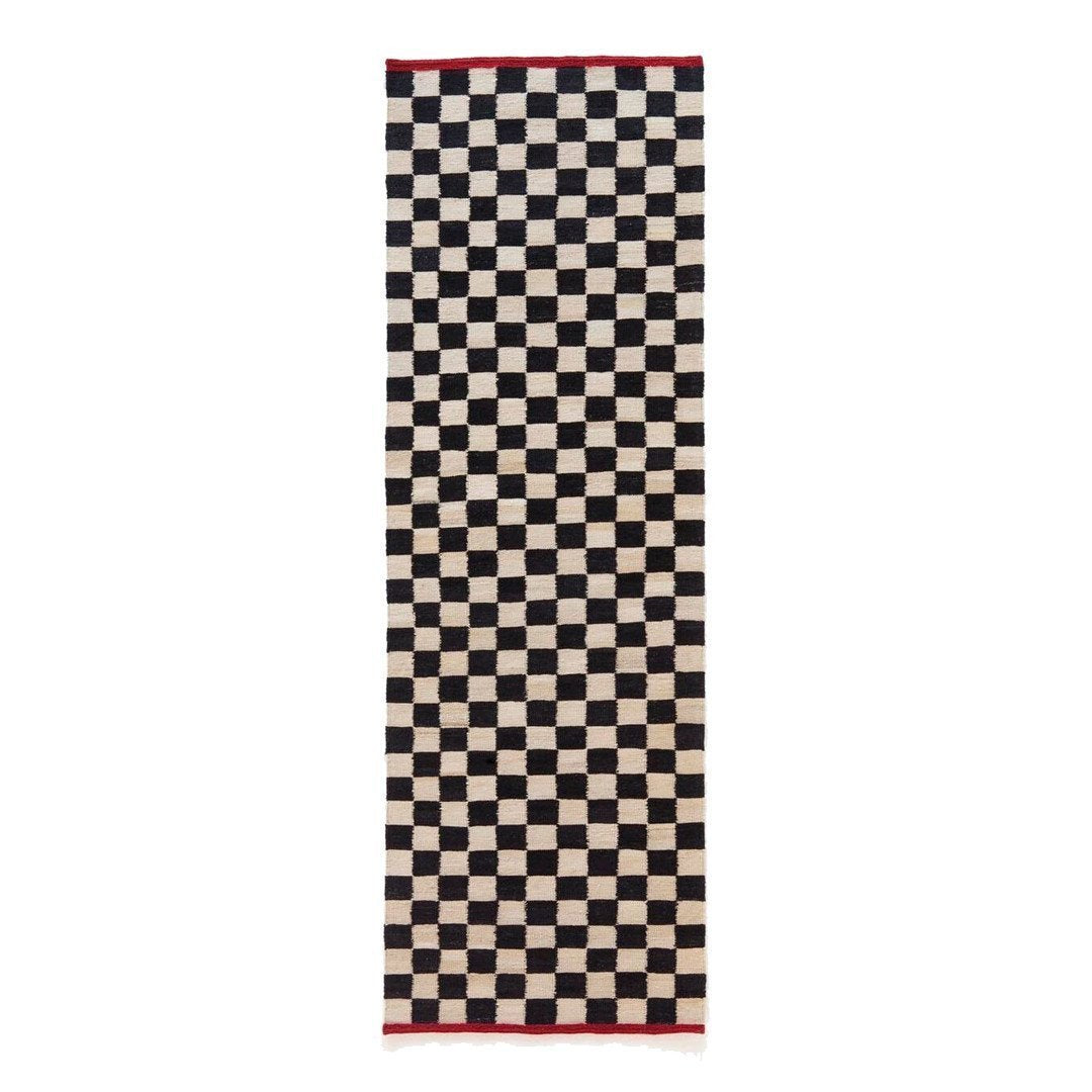 Black and cream checkered pattern rug with a red border, perfect for adding a stylish touch to any space.